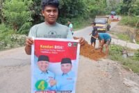 Warga Kelurahan Labibia berfoto sambil memegang baleho AJP-ASLI usai menerima material timbunan. Foto : Ist