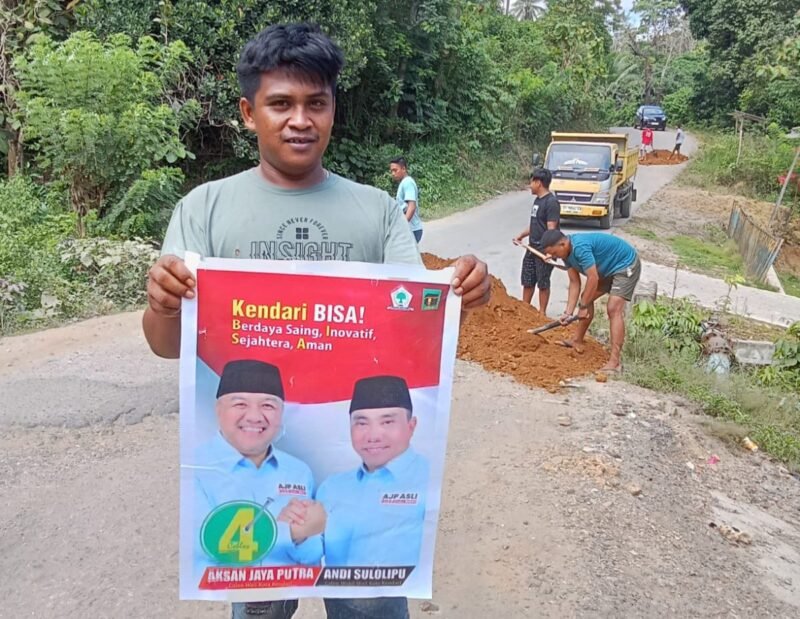 Warga Kelurahan Labibia berfoto sambil memegang baleho AJP-ASLI usai menerima material timbunan. Foto : Ist